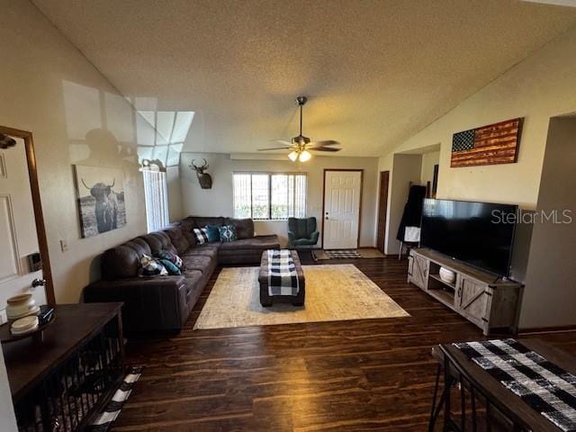 living room featuring dark wood finished floors, vaulted ceiling, a textured ceiling, and ceiling fan