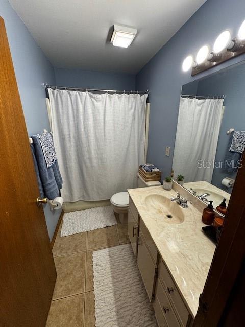 full bath featuring toilet, curtained shower, tile patterned flooring, and vanity