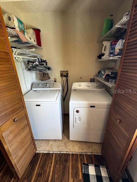 laundry room with light wood-style floors, washer and dryer, laundry area, and a textured ceiling