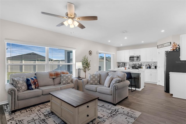 living room featuring light wood finished floors, a ceiling fan, and recessed lighting