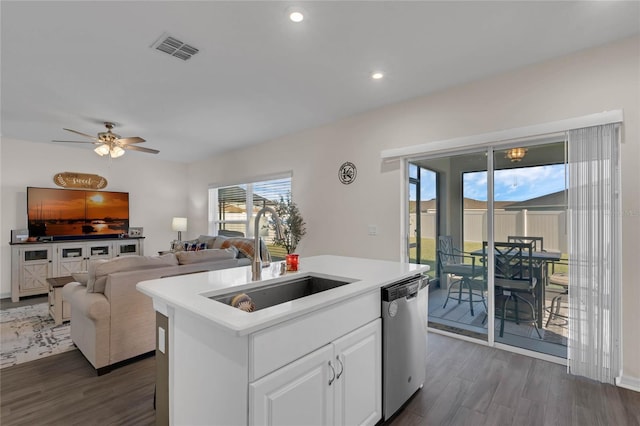 kitchen featuring a sink, visible vents, stainless steel dishwasher, dark wood finished floors, and a center island with sink