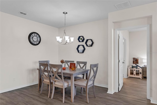 dining space with visible vents, a notable chandelier, baseboards, and wood finished floors