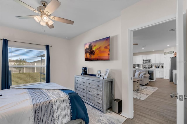 bedroom with visible vents, ceiling fan, freestanding refrigerator, and light wood-style floors