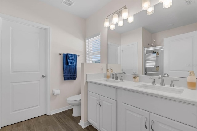 full bathroom featuring toilet, wood finished floors, a sink, and visible vents