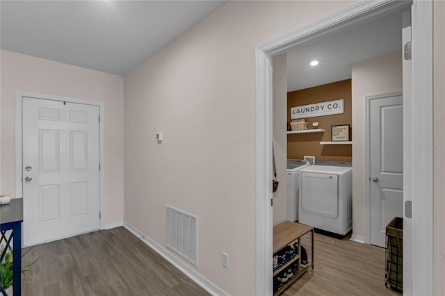 clothes washing area featuring laundry area, wood finished floors, washing machine and clothes dryer, and visible vents