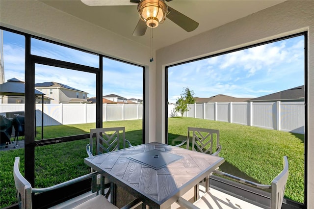 sunroom / solarium featuring ceiling fan and a residential view