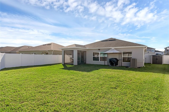 rear view of property with a fenced backyard, a lawn, and stucco siding