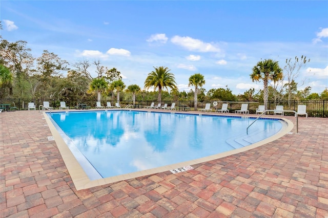 community pool with a patio area and fence