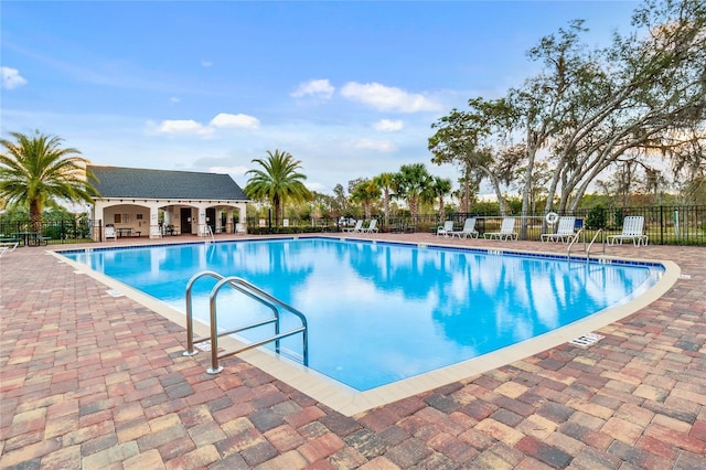 pool with a patio area and fence