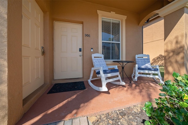 doorway to property featuring stucco siding and a porch