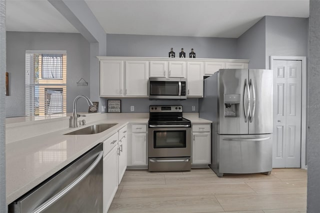 kitchen with a sink, white cabinetry, appliances with stainless steel finishes, and light countertops