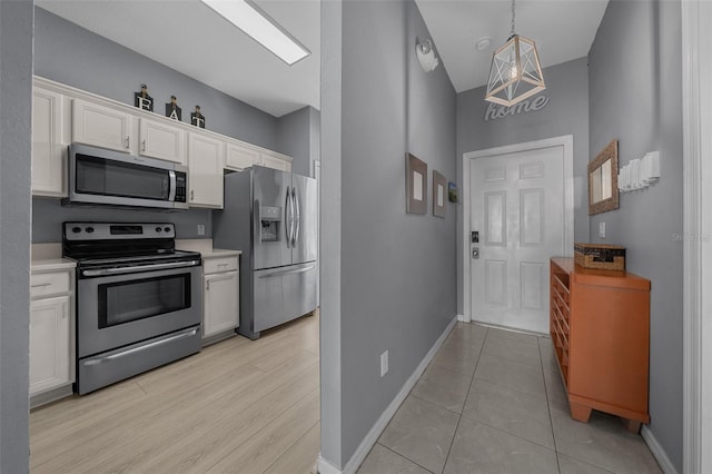 kitchen with baseboards, pendant lighting, light countertops, appliances with stainless steel finishes, and white cabinets