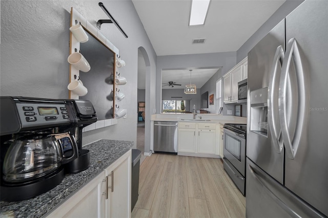 kitchen featuring visible vents, a sink, stainless steel appliances, white cabinetry, and light wood-type flooring