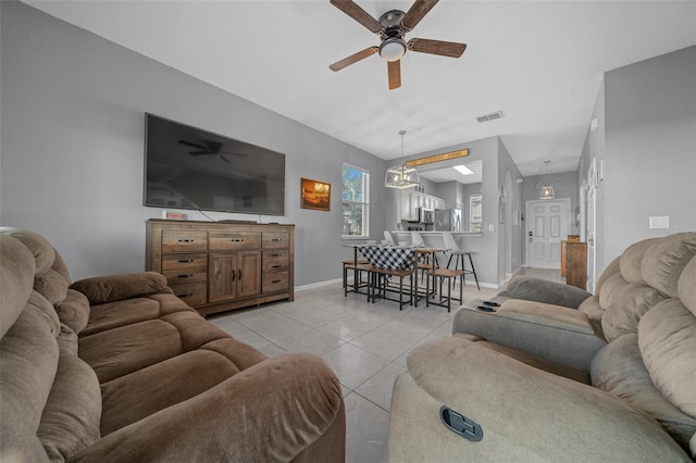 living room featuring light tile patterned floors, visible vents, baseboards, and ceiling fan with notable chandelier