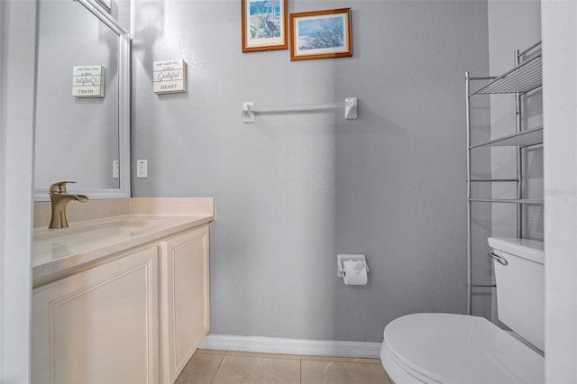 half bath with tile patterned floors, toilet, vanity, and baseboards