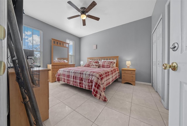 bedroom featuring light tile patterned floors, ceiling fan, a closet, and baseboards