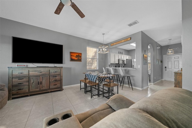 living room with light tile patterned floors, visible vents, baseboards, and a ceiling fan