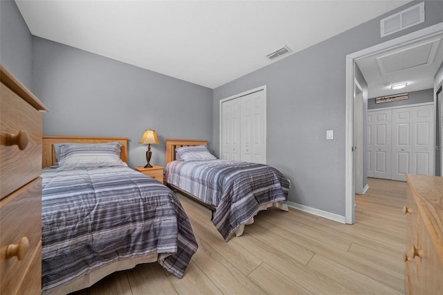 bedroom featuring light wood finished floors, visible vents, baseboards, and a closet