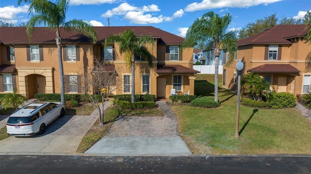 view of front facade with a front yard, fence, a residential view, and stucco siding