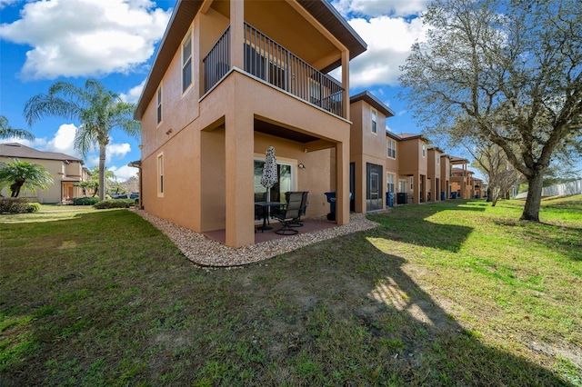 back of house with a patio area, stucco siding, a yard, and a balcony