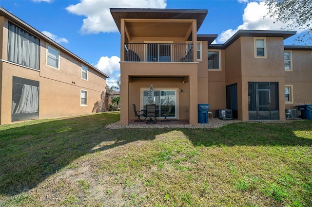 rear view of house featuring central air condition unit, stucco siding, a yard, a balcony, and a patio area