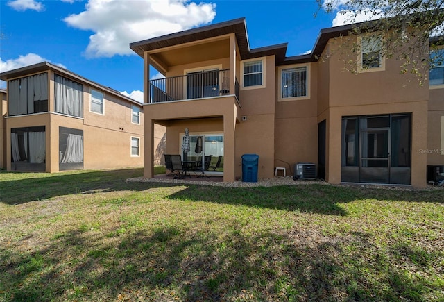 rear view of house with central air condition unit, a patio area, a lawn, and stucco siding