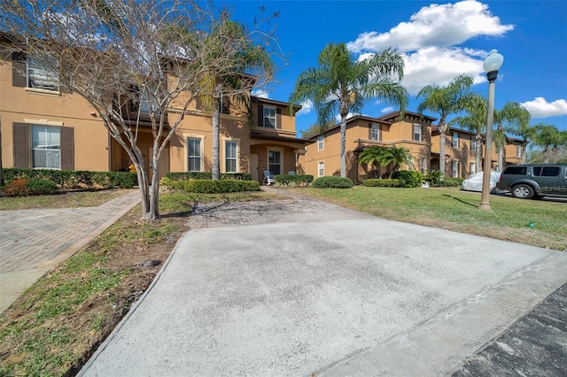 view of front of house with stucco siding and a front lawn