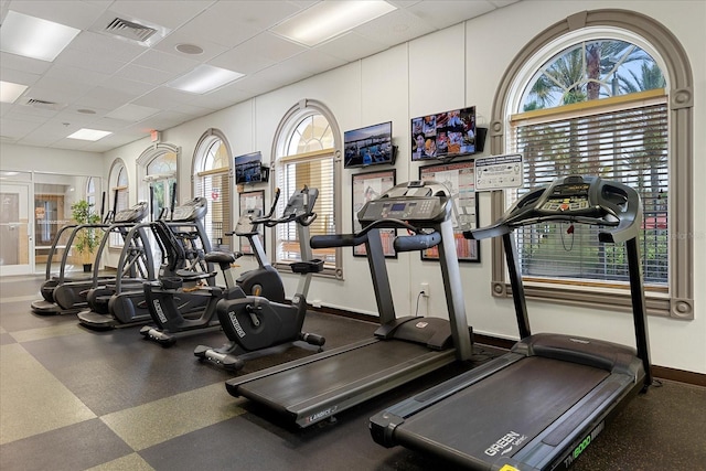 workout area with a drop ceiling, visible vents, and baseboards