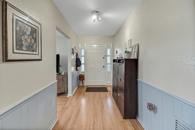 foyer entrance with light wood-type flooring and wainscoting