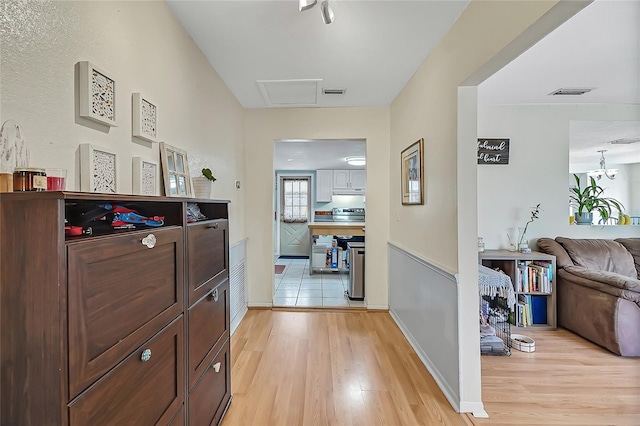 hallway featuring light wood-style floors, baseboards, and visible vents