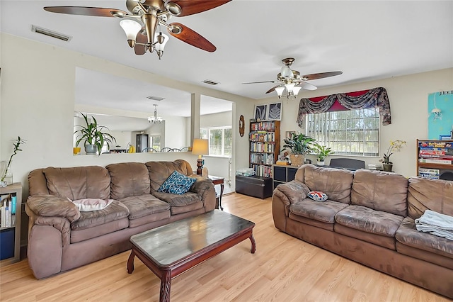 living area with a ceiling fan, visible vents, and wood finished floors