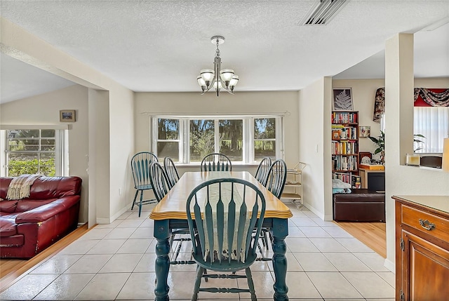 dining room with light tile patterned floors, a textured ceiling, visible vents, and a notable chandelier