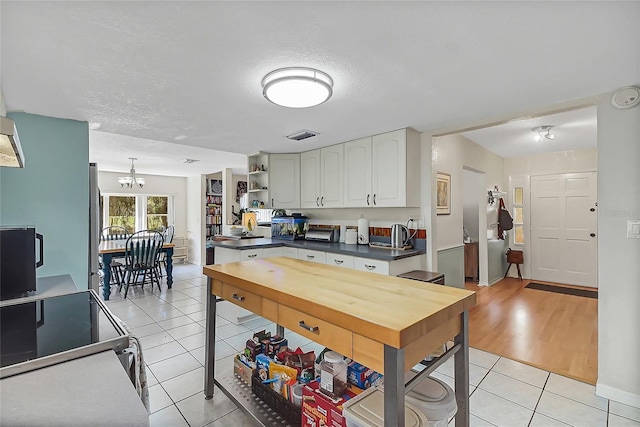 kitchen featuring dark countertops, light tile patterned flooring, open shelves, and white cabinetry