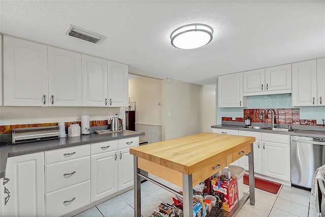 kitchen with dishwasher, white cabinets, a sink, and light tile patterned flooring