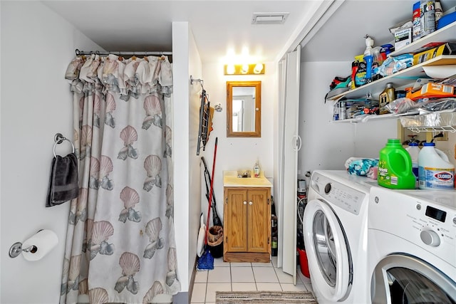 washroom featuring light tile patterned floors, a sink, washing machine and clothes dryer, and visible vents