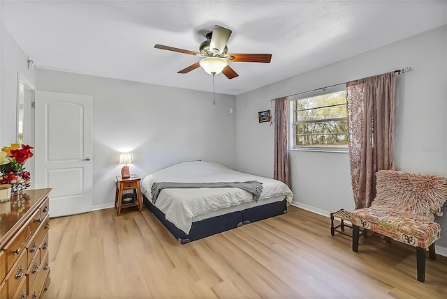 bedroom featuring a ceiling fan, light wood-style flooring, and baseboards