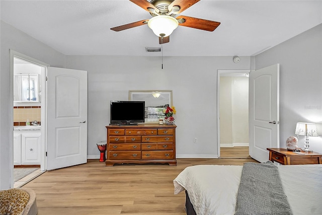 bedroom featuring visible vents, light wood-style flooring, a ceiling fan, ensuite bath, and baseboards