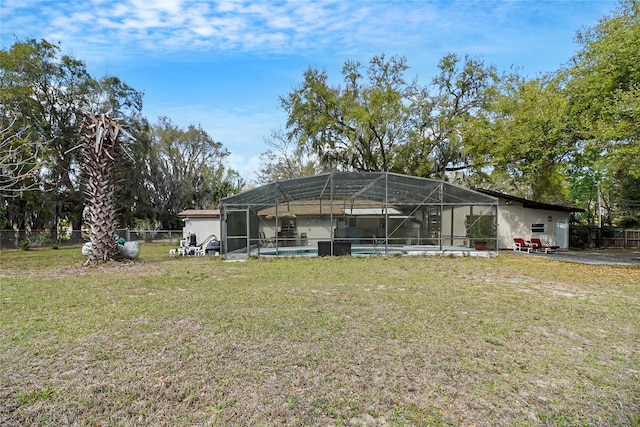 rear view of property featuring glass enclosure, fence, and a yard