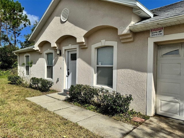 property entrance with a garage and stucco siding