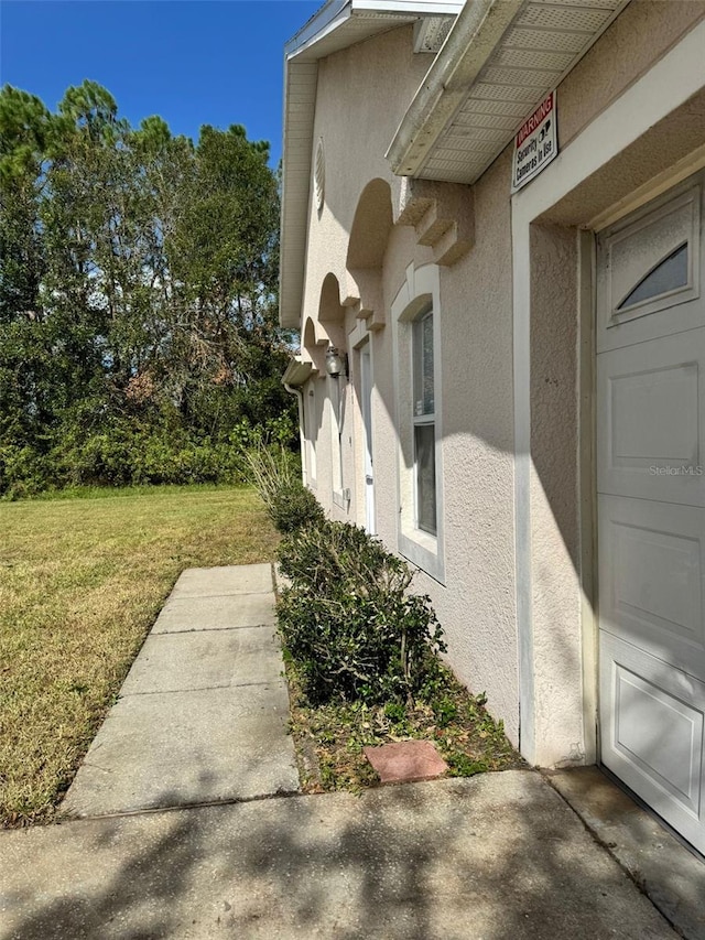 view of side of property featuring a garage, a yard, and stucco siding