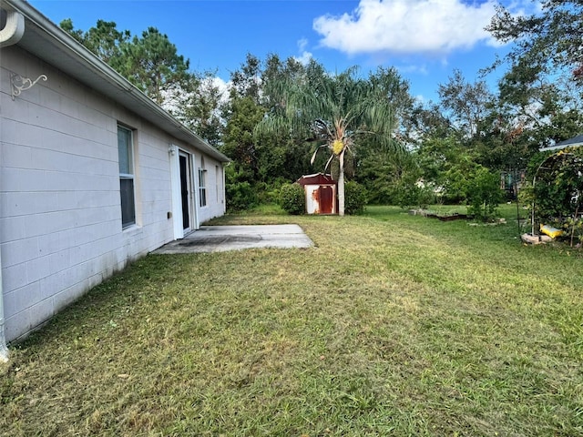 view of yard featuring an outbuilding, a patio, and a storage shed