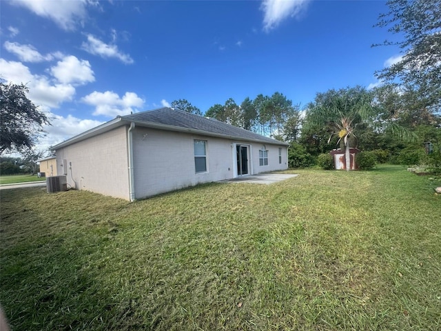 rear view of property featuring an outbuilding, a patio, concrete block siding, a yard, and a storage unit