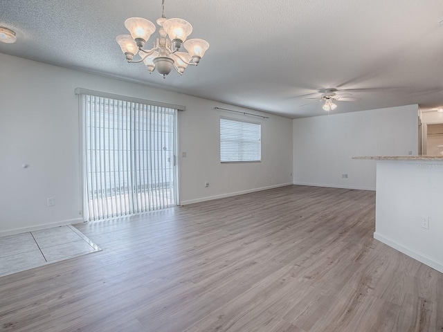 unfurnished living room featuring light wood finished floors, baseboards, a textured ceiling, and ceiling fan with notable chandelier