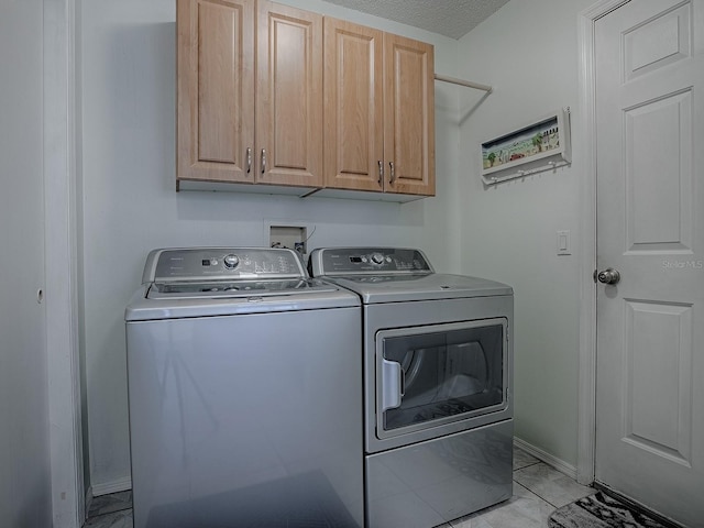 clothes washing area featuring baseboards, cabinet space, and washing machine and clothes dryer