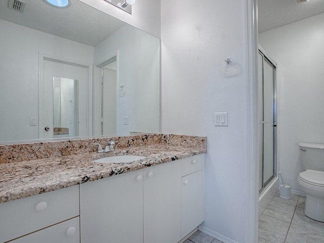 bathroom featuring visible vents, toilet, a textured ceiling, vanity, and a shower stall