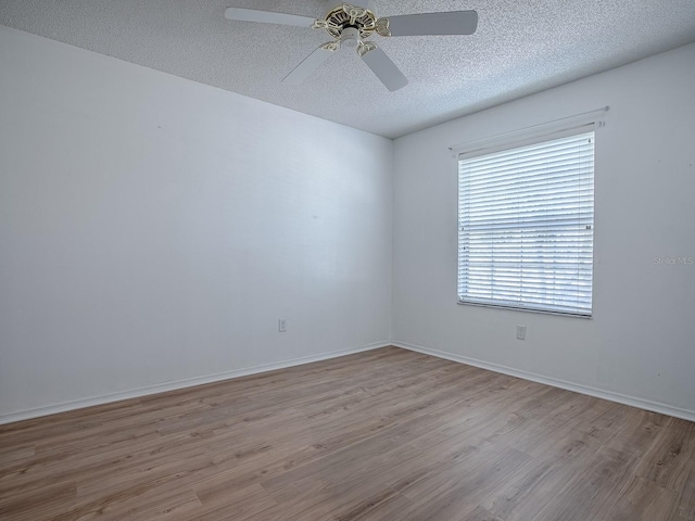 unfurnished room with a ceiling fan, a textured ceiling, baseboards, and wood finished floors