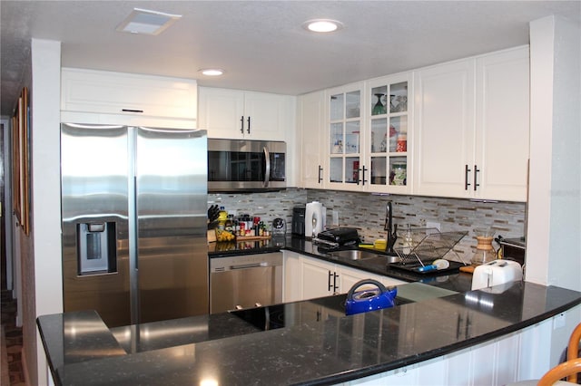 kitchen featuring appliances with stainless steel finishes, backsplash, a sink, and glass insert cabinets