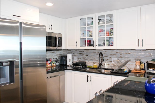 kitchen featuring decorative backsplash, appliances with stainless steel finishes, glass insert cabinets, white cabinets, and a sink