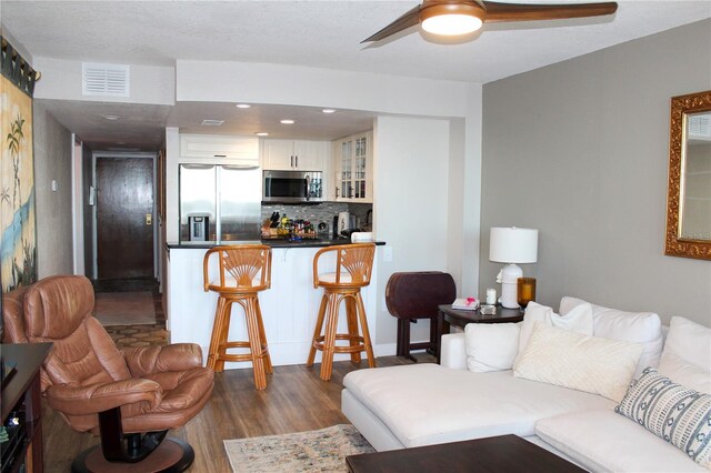 living room featuring visible vents, dark wood finished floors, and ceiling fan