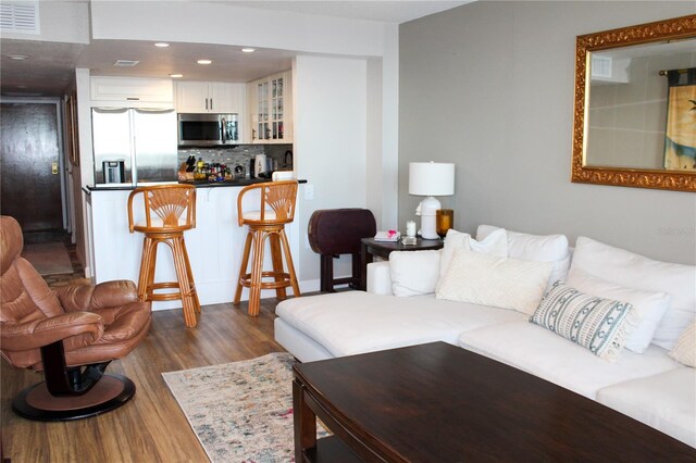 living area with dark wood finished floors, visible vents, and recessed lighting